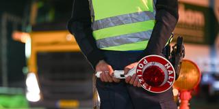 Polizisten kontrollieren den Grenzverkehr. Ein Polizist mit einer Polizeikelle. (Foto: IMAGO / diebildwerft)