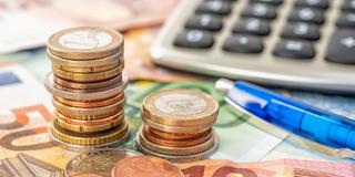 Euro Geldscheine und Münzen liegen auf einem Tisch, mit einer Taschenrechner und einem Stift (Foto: IMAGO / Shotshop)