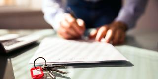 Jemand unterschreibt einen Vertrag, Schlüssel liegen auf dem Tisch (Foto: IMAGO / Panthermedia)