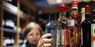 Eine junge Frau greift im Supermarkt nach alkoholischen Getränken. (Foto: IMAGO / photothek)