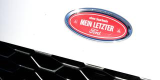 Ein Protest-Aufkleber „ohne Saarlouis – mein letzter Ford“ auf dem Marken-Emblem eines Fords (Foto: IMAGO / BeckerBredel)