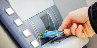 Jemand steckt eine Bankkarte in einen Geldautomat (Foto: IMAGO / YAY Images)