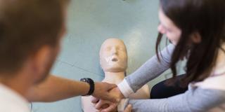 Schüler lernen an einer Puppe die Handgriffe zur Reanimation einer Person. (Foto: IMAGO / Zoonar / Matej Kastelic )