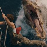 Aus dem Wasser heraus schnappt ein Dino nach einer Person. Diese klammert sich an ein Geländer.  (Foto: IMAGO / Cinema Publishers Collection)