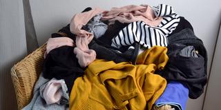 Kleidungsstücke liegen unordentlich auf einem Stuhl (Foto: IMAGO / Zoonar)