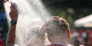 Athlet kühlt sich bei drückender Hitze unter einer Dusche mit kaltem Wasser ab. (Foto: IMAGO / Ralph Peters)