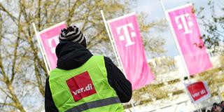 Streikende Verdi-Mitglieder vor Werbefahnen der Telekom (Foto: IMAGO / Hanno Bode)