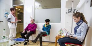 Personen in einem Wartezimmer werden von Arzthelferin aufgerufen (Foto: IMAGO / Jochen Tack)