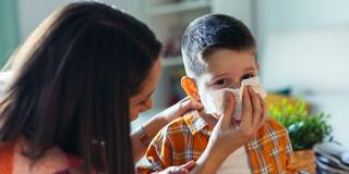 Eine Frau hält einem Kind ein Taschentuch vor die Nase (Foto: IMAGO / Westend61)