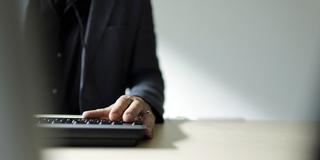 Ein Mann steht am Schreibtisch vor einem Computer (Foto: IMAGO / photothek)