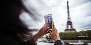 Eine junge Frau fotografiert den Eiffelturm (Foto: IMAGO / Westend61)