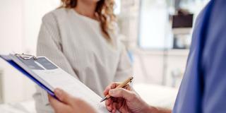 Medizinische Fachkraft notiert Daten und spricht mit einer Patientin (Foto: IMAGO / HalfPoint Images)