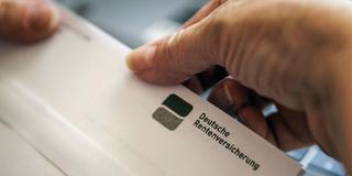 Eine Frau öffnet einen Brief der Deutschen Rentenversicherung (Foto: IMAGO / photothek)