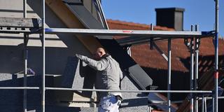 Ein Facharbeiter bringt eine Fassadendämmung an einem Eigenheim an. (Foto: IMAGO / Sven Simon)