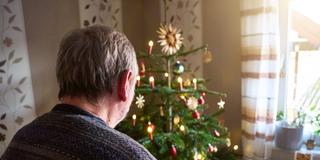 Mann betrachtet Weihnachtsbaum. (Foto: IMAGO / Bihlmayerfotografie)