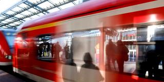 Schatten von wartenden Fahrgästen am Gleis fallen auf eine einfahrenden Regionalbahn (Foto: IMAGO / Panama Pictures)