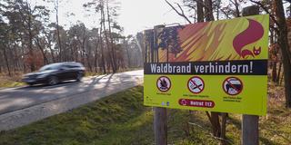 Ein Auto fährt an einer Hinweistafel "Waldbrand verhindern!" vorbei. (Foto: IMAGO / Bernd März)