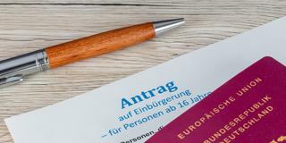 Nahaufnahme von einem Antrag auf Einbürgerung in die Bundesrepublik Deutschland und ein deutscher Reisepass (Foto: IMAGO / Herrmann Agenturfotografie)