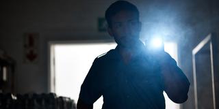 Jemand leuchtet mit einer Taschenlampe im dunklen Büro (Foto: IMAGO / YAY Images)