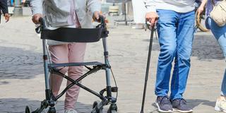 Zwei Senioren mit Rollator und Gehstock in einer Fußgängerzone (Foto: IMAGO / Michael Gstettenbauer)