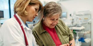 Eine Ärztin zeigt einer Patienting in der Praxis ihre elektronische Patientenakte auf dem Smartphone (Foto: IMAGO / HalfPoint Images)