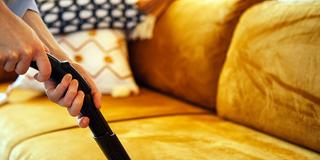 Jemand saugt ein Polstermöbel ab (Foto: IMAGO / Zoonar)