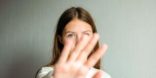 Eine Frau streckt selbstbewusst ihre Hand zur Abwehr vor das Gesicht (Foto: IMAGO / Zoonar)