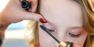 Ein Kind bekommt Wimperntusche aufgetragen (Foto: IMAGO / Zoonar)