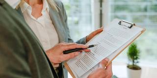 Zwei Personen besprechen Unterlagen auf einem Klemmbrett (Foto: IMAGO / Westend61)