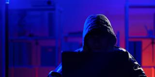 Unkenntliche Person mit Kapuze vor Laptop (Foto: IMAGO / Zoonar)