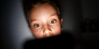 Symbolfoto: Gestellte Aufnahme zum Thema Mediennutzung bei Kindern. Ein Kind schaut im Dunkeln auf das Display eines Smartphones (Foto: IMAGO / photothek)