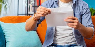 Jemand hält einen geöffneten Briefumschlag in den Händen (Foto: IMAGO / YAY Images)