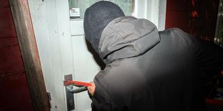 Jemand bricht eine Tür mit einem Hebeeisen auf (Foto: IMAGO / Bihlmayerfotografie)