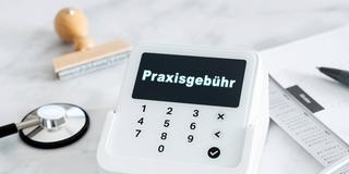 Symbolfoto zur Praxisgebühr mit Anzeige auf einem Terminal, daneben Gesundheitskarte und Stethoskop (Foto: IMAGO / Bihlmayerfotografie)