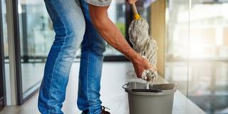 Ein Mann wringt einen Putzlappen über dem Eimer aus (Foto: IMAGO / YAY Images)