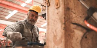 Ein Senior wartet eine Maschine in einem Unternehmen. (Foto: IMAGO / Zoonar / Sunan Wongsa)