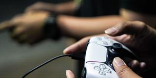 Jemand spielt mit einem Playstation-Controller (Foto: IMAGO / NurPhoto)