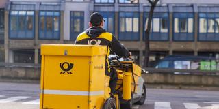 Ein Briefträger der Deutsche Post unterwegs mit seinem Fahrrad. (Foto: IMAGO / Arnulf Hettrich)