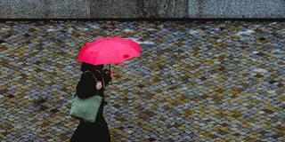 Eine Frau mit Regenschirm bei trübem Tageslicht (Foto: IMAGO / photothek)