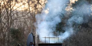 Ein qualmender Schornstein bei aufgehender Wintersonne (Foto: IMAGO / Gottfried Czepluch)