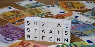 Geldscheine und Buchstabenwürfel mit Schriftzug Sozialstaatsreform (Foto: IMAGO / Steinach)