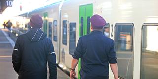 Zwei Bahnmitarbeiter gehen einen Bahnsteig entlang. (Foto: IMAGO / Gottfried Czepluch)