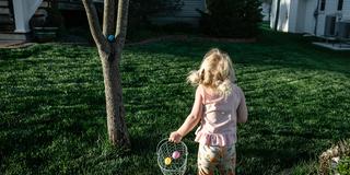 Ein Kind sammelt Ostereier im Garten (Foto: IMAGO / Cavan Images)