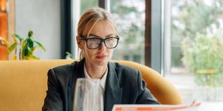 Eine Frau sitzt in einem Restaurant und liest die Speisekarte (Foto: IMAGO / Zoonar)