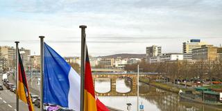 Saaländische, deutsche und französische Flaggen vor Saarbrücker Panorama (Foto: IMAGO / BeckerBredel)