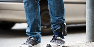 Mann mit Fußfessel am Knöchel. (Foto: IMAGO / brennweiteffm)