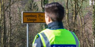 Grenzkontrolle. Ein Polizist steht auf deutscher Seite an der Grenze vor dem Wegweiser nach Luxemburg (Foto: IMAGO / Reichwein)