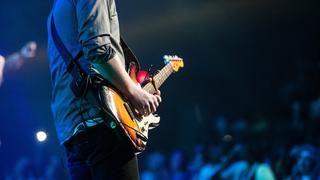Ein Mann steht auf einer Bühne vor Publikum und spielt Gitarre  (Foto: pixabay.com)