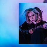 Eine Frau sitzt mit einer Gitarre in buntem Licht. (Foto: Pressefoto/Laura di Natali)
