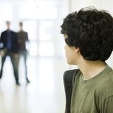Ein Junge steht im Vordergrund und schaut zu drei Personen, die im Hintergrund stehen und ihn anschaun (Foto: imagoimages/PhotoAlto)